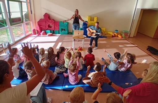 Kindergartengruppe Kita St. Marien Gruppe von Kindern in einer Sitzugruppe mit Mann, der Gitarre spielt