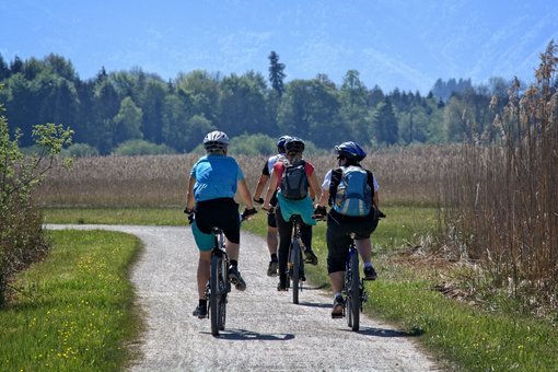 Personen fahren bei schönem Wetter mit dem Fahrrad auf einem Feldweg 
