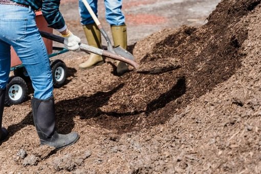 Mulcharbeiten Personen mit Schaufel arbeiten mit Mulch