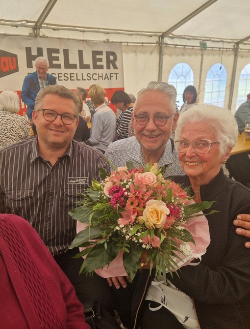 Vertreter der Bank und Bürgermeister überreichen der ältesten Bürgerin einen Blumenstrauß