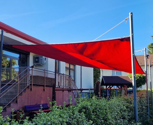Großes rotes Sonnensegel über Außen-Spielbereich